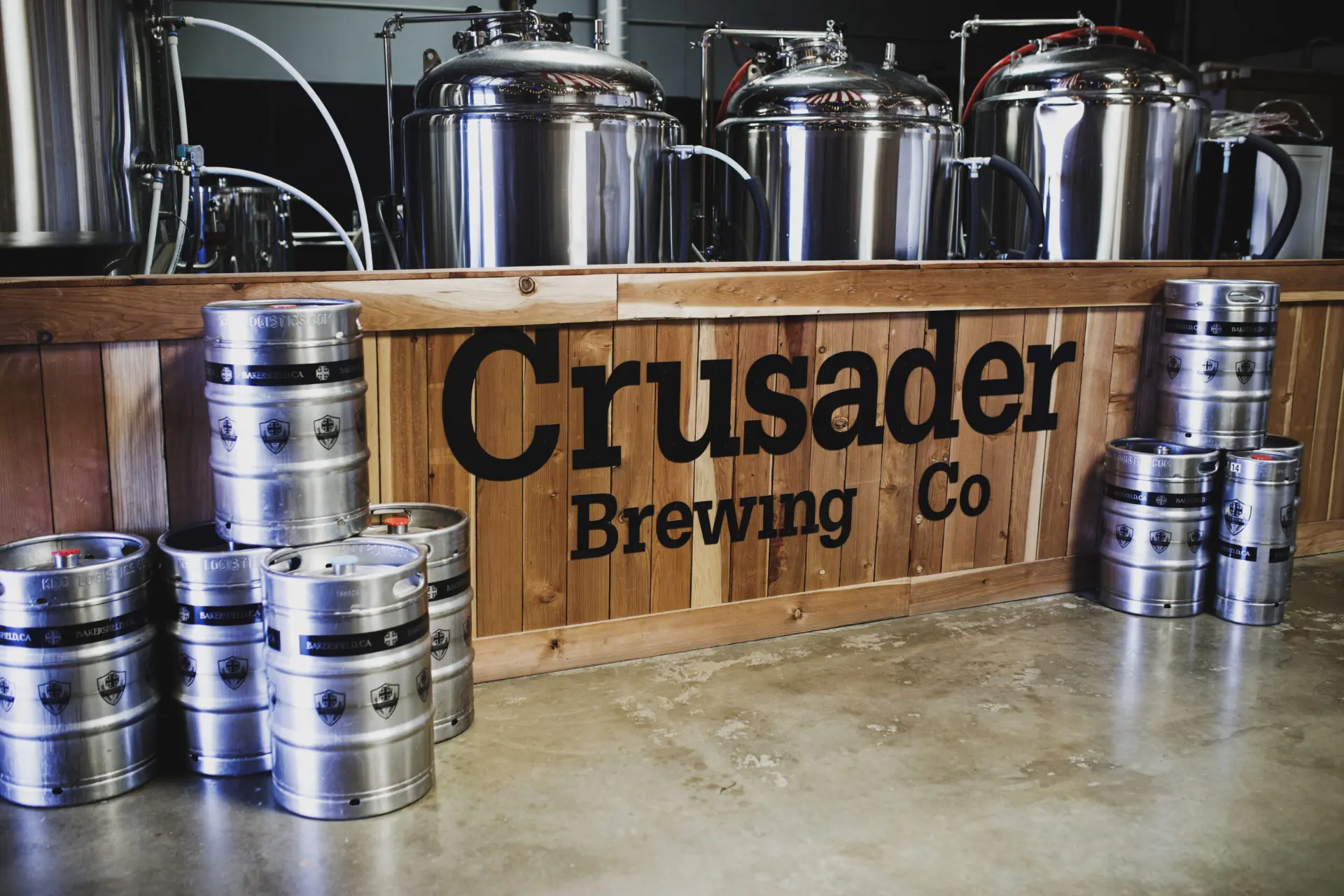 Crusader Brewing kegs stacked in front of the brewhouse tanks